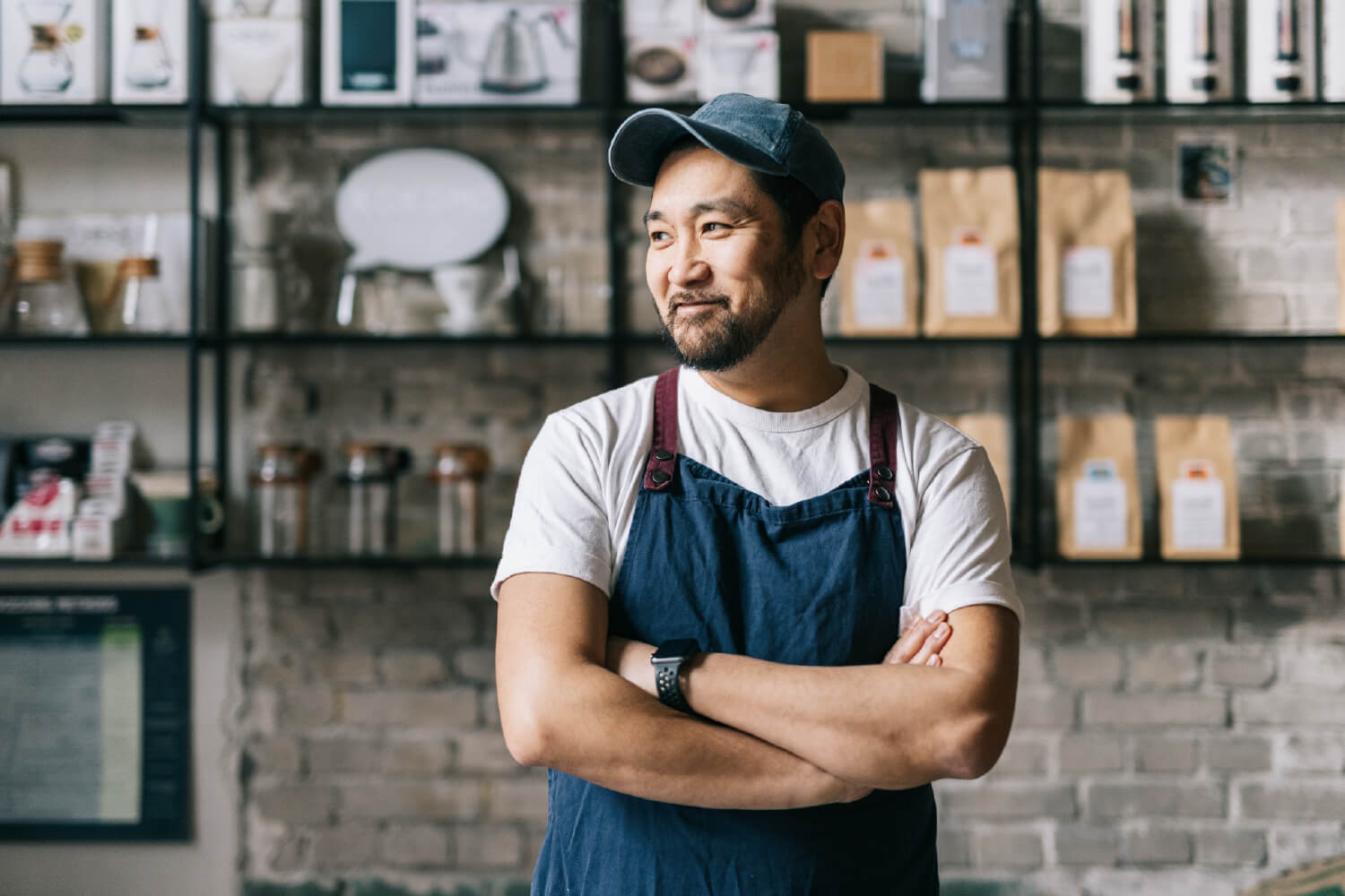 A make business owner standing in his shop, with his arms folded