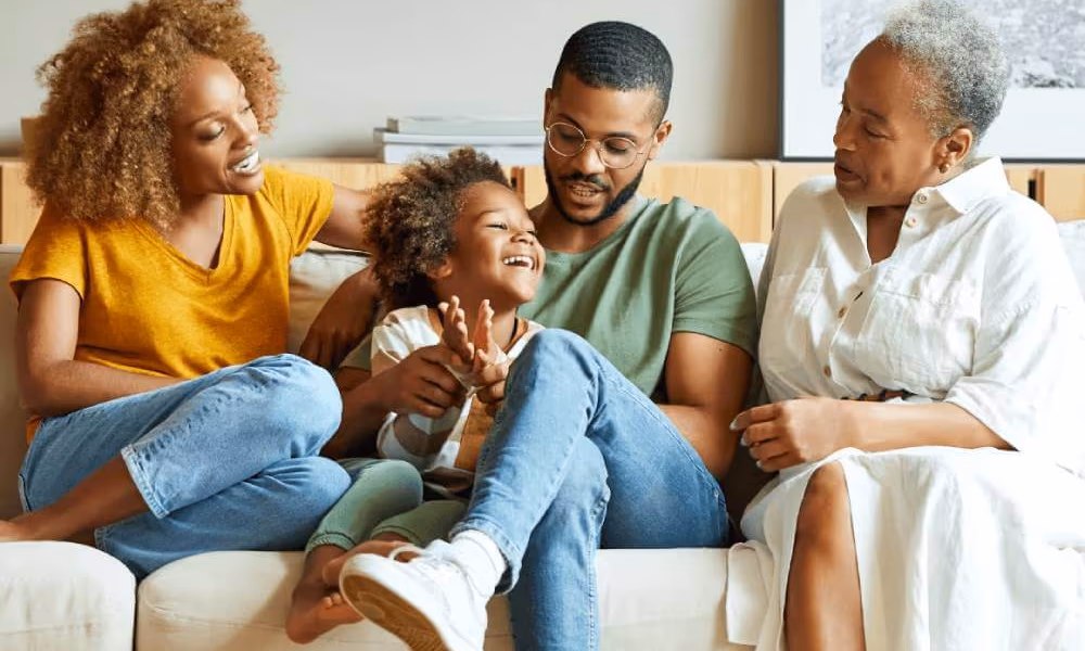 Happy mother, child, father and grandmother sitting on a couch.