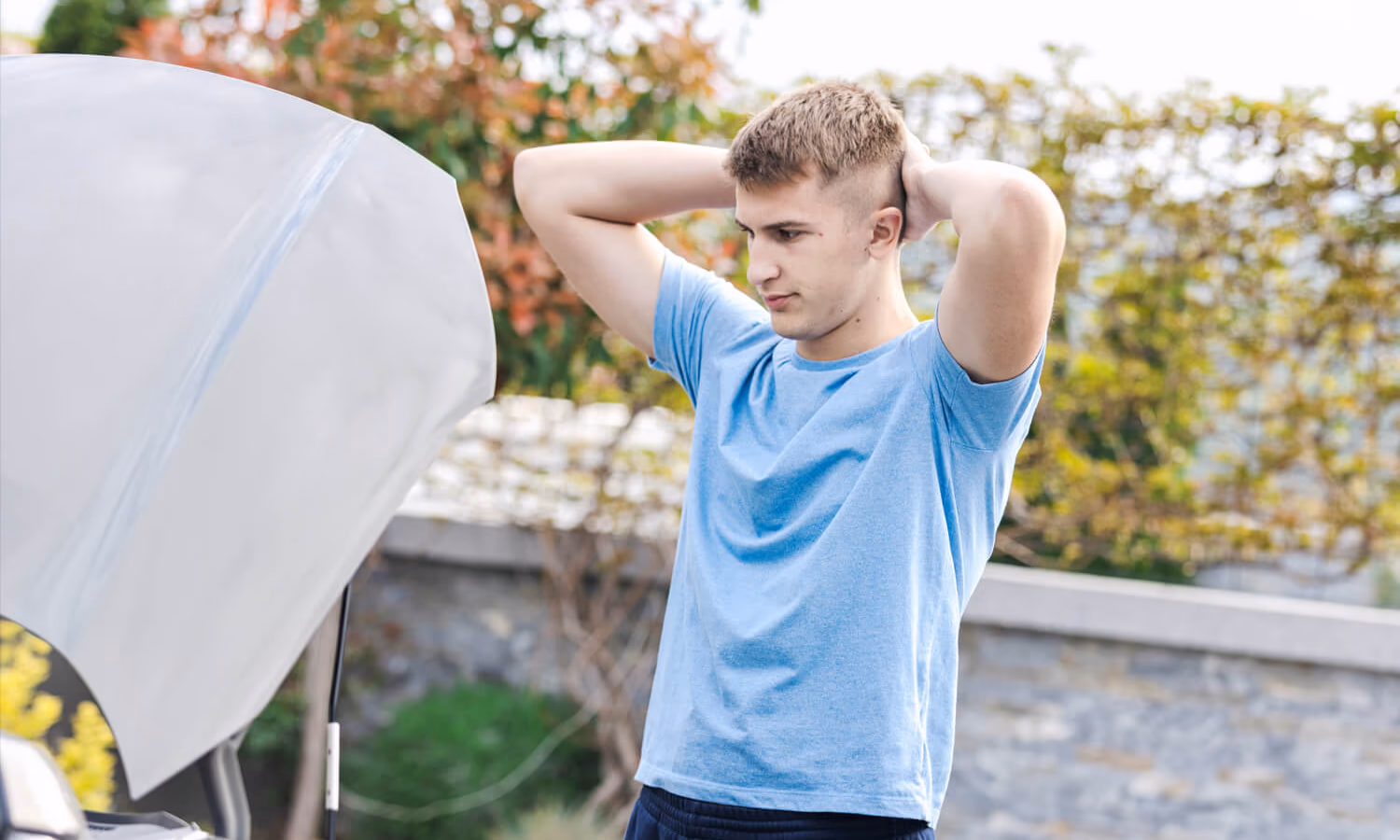 Frustrated Young Man Examining Car Breakdown in Suburban Environment