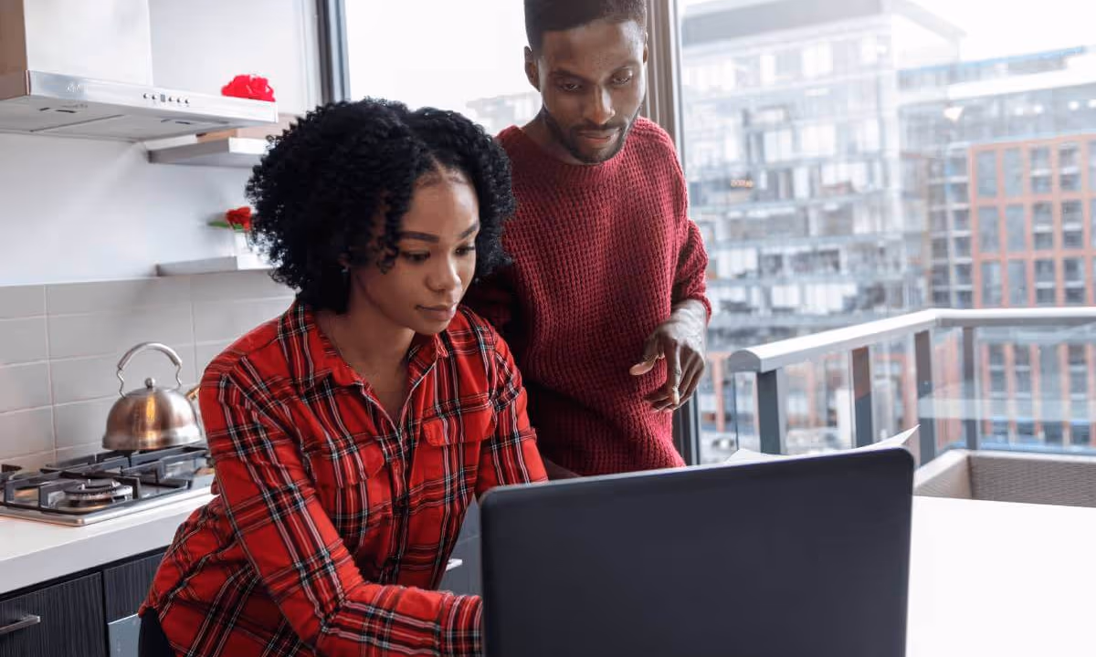 Couple in their kitchen working on their digital real estate businessn looking at his LegalShield app homescreen on his iPhone