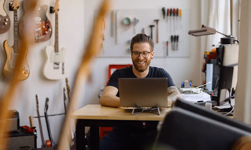 A small business owner on his laptop in a guitar shop, setting up an EIN for his LLC.