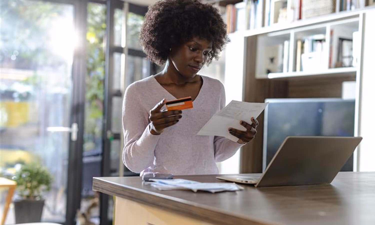 Woman managing finances online with laptop and credit card at home