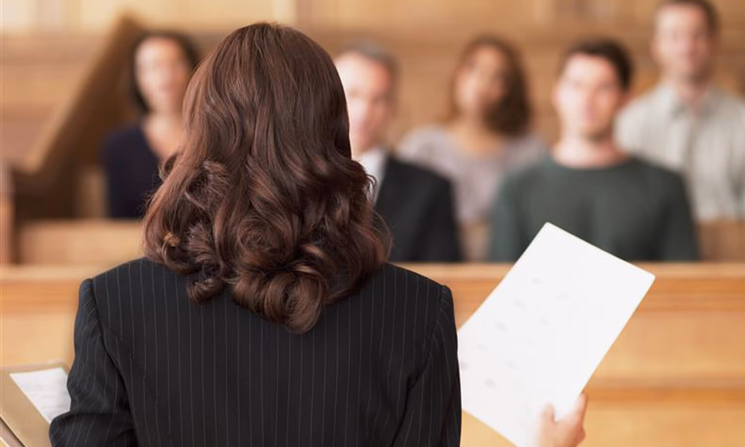 Lawyer holding document and speaking to jury in courtroom