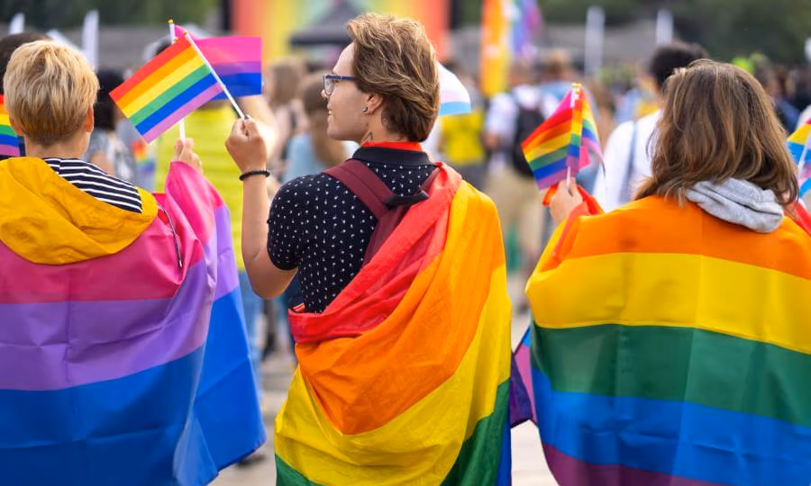 People wearing gay pride rainbow flags in street
