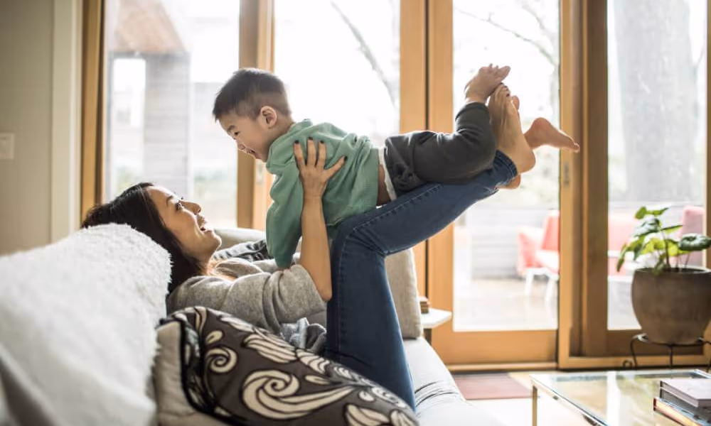 Mom laughing and playing with son on the couch