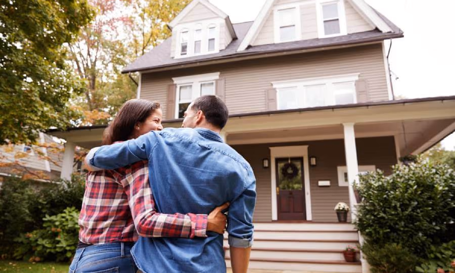 Homeowners in the front yard embracing and looking at their home|Elderly couple looking at documents and laptop computer concerned abou t what is a lien on a house.|Mature couple look at a mortgage lien legal document.