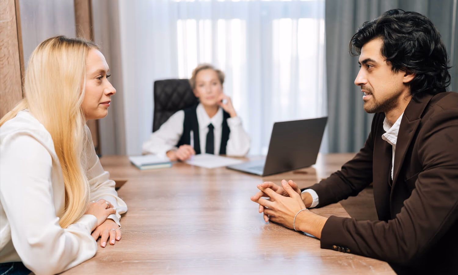 Sad young man and woman getting divorced sitting at table with layer in office