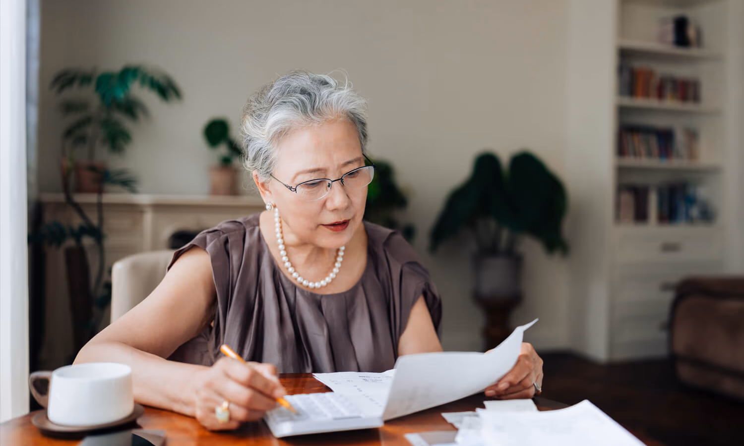 Close up of Asian senior woman calculating financial bills and receipts