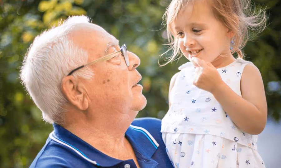 Grandpa holding his young granddaughter outside|Elderly woman holding a pie|Elderly woman holding a pie