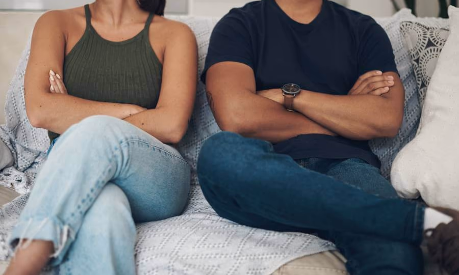 Divorcing couple next to each other with arms crossed on couch