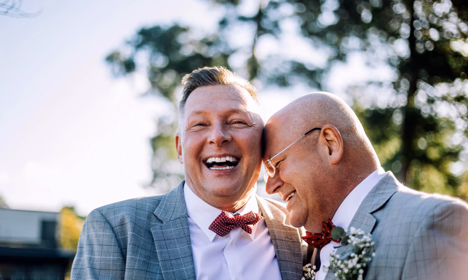 Cheerful newlywed gay couple laughing together at wedding