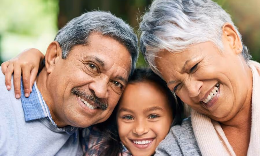 Grandparents hugging their granddaughter.