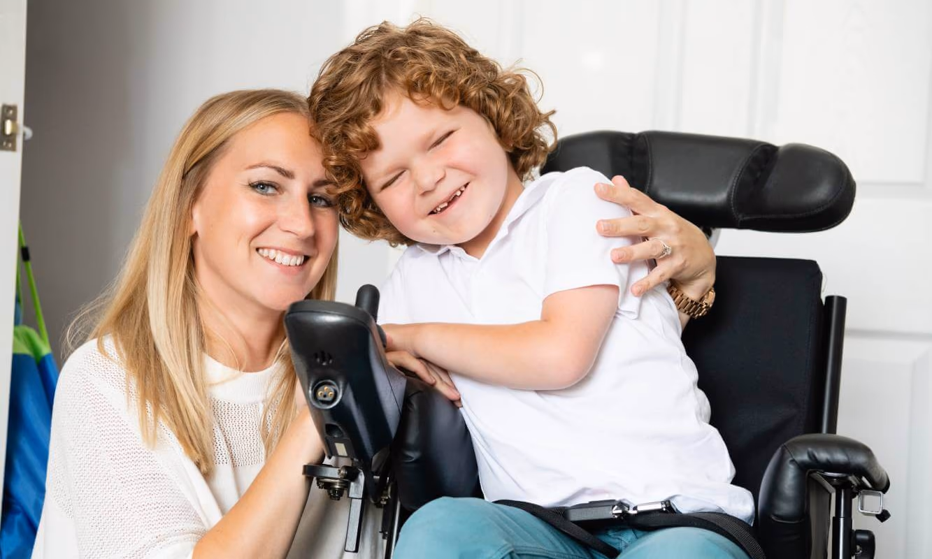 Young boy in a wheelchair sitting next to his mother