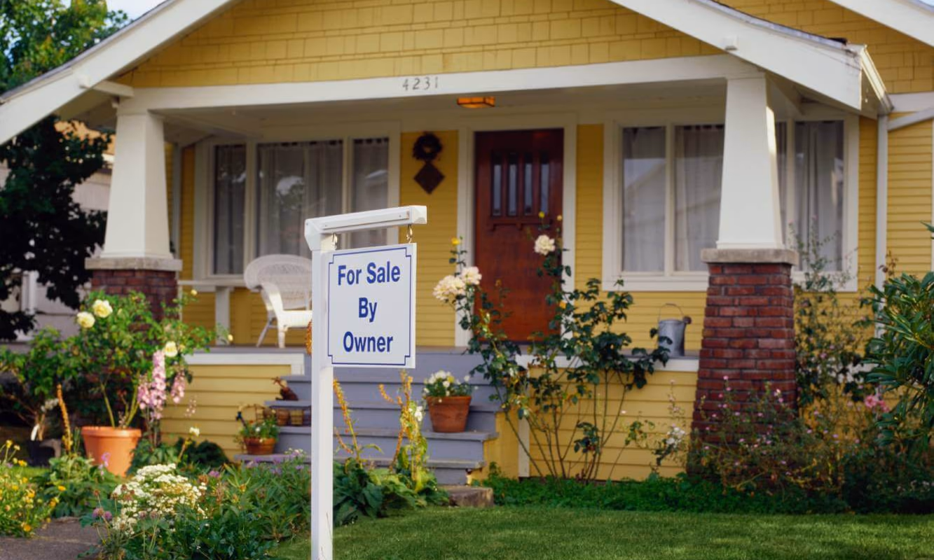 yellow house with a house for sale by owner sign in the front yard