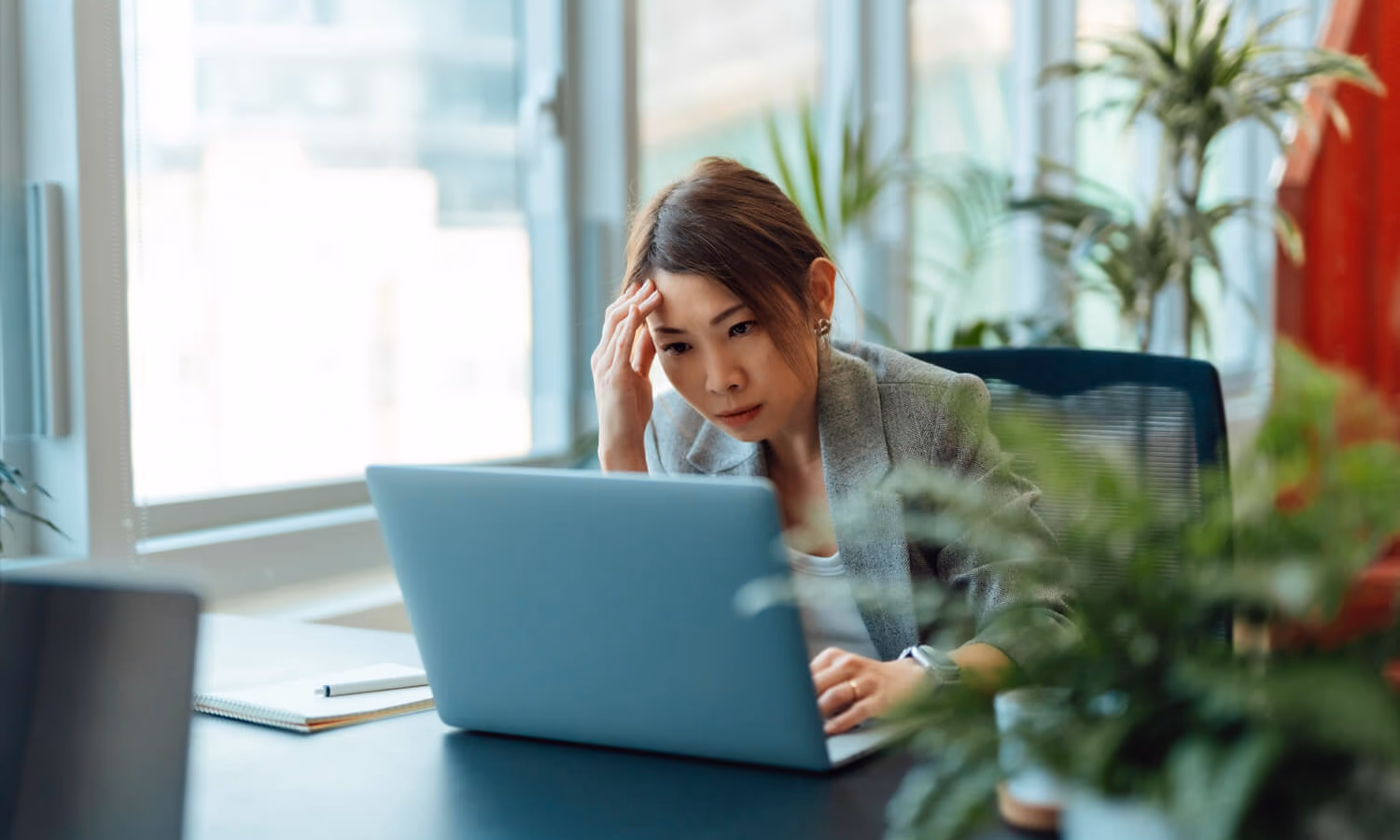 Tired Asian businesswoman working on a laptop computer in the office