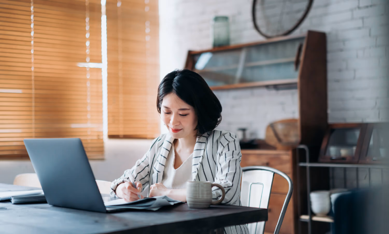 A woman signing a document at a laptop.
