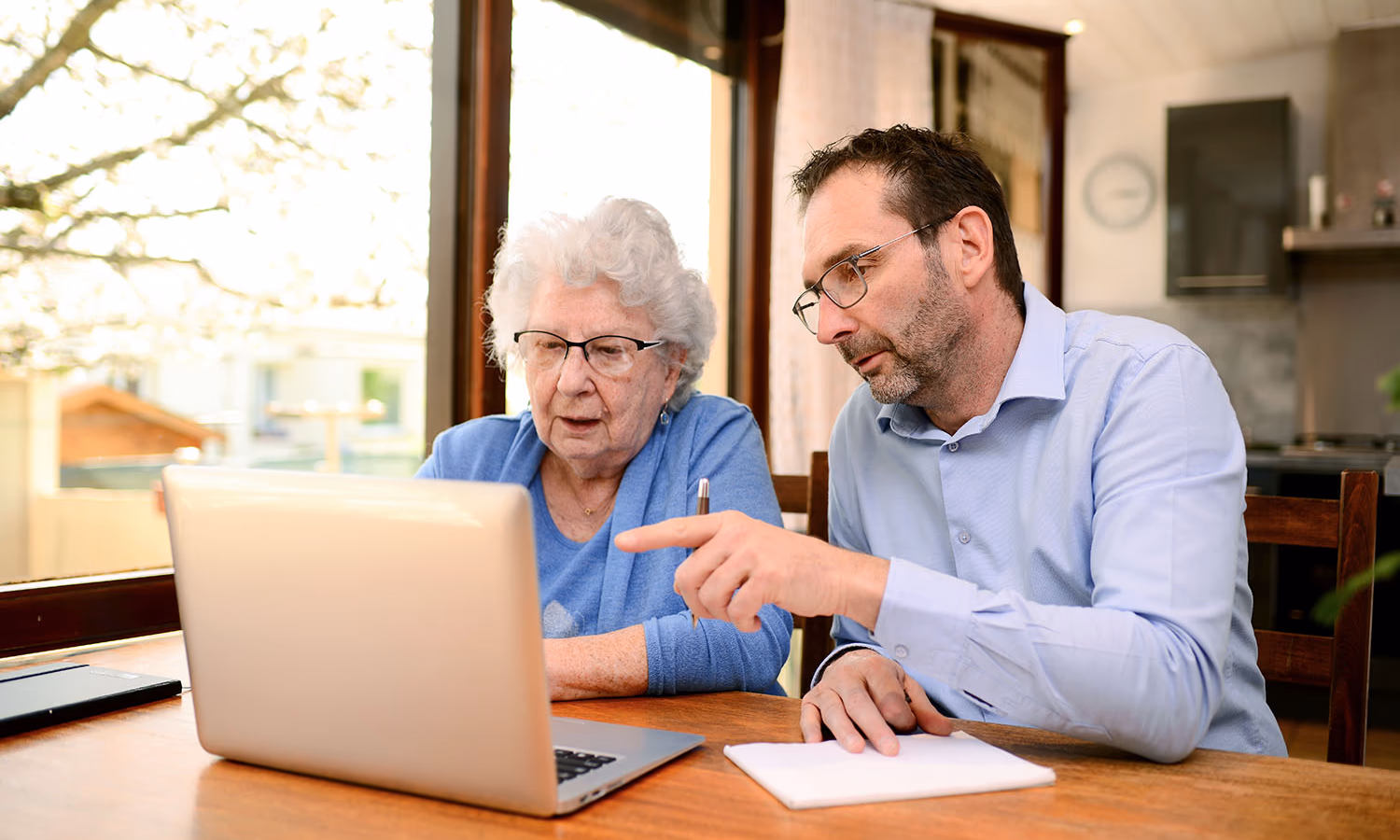 A photograph of an older woman and her adult daughter sitting together on a sofa and/or reviewing a document.