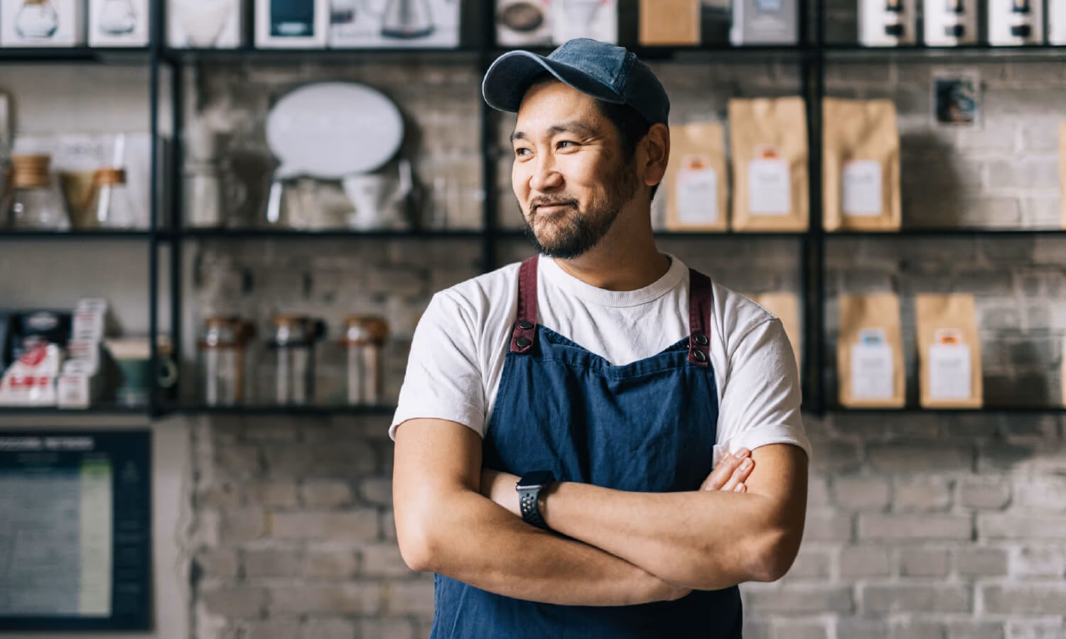 A make business owner standing in his shop, with his arms folded