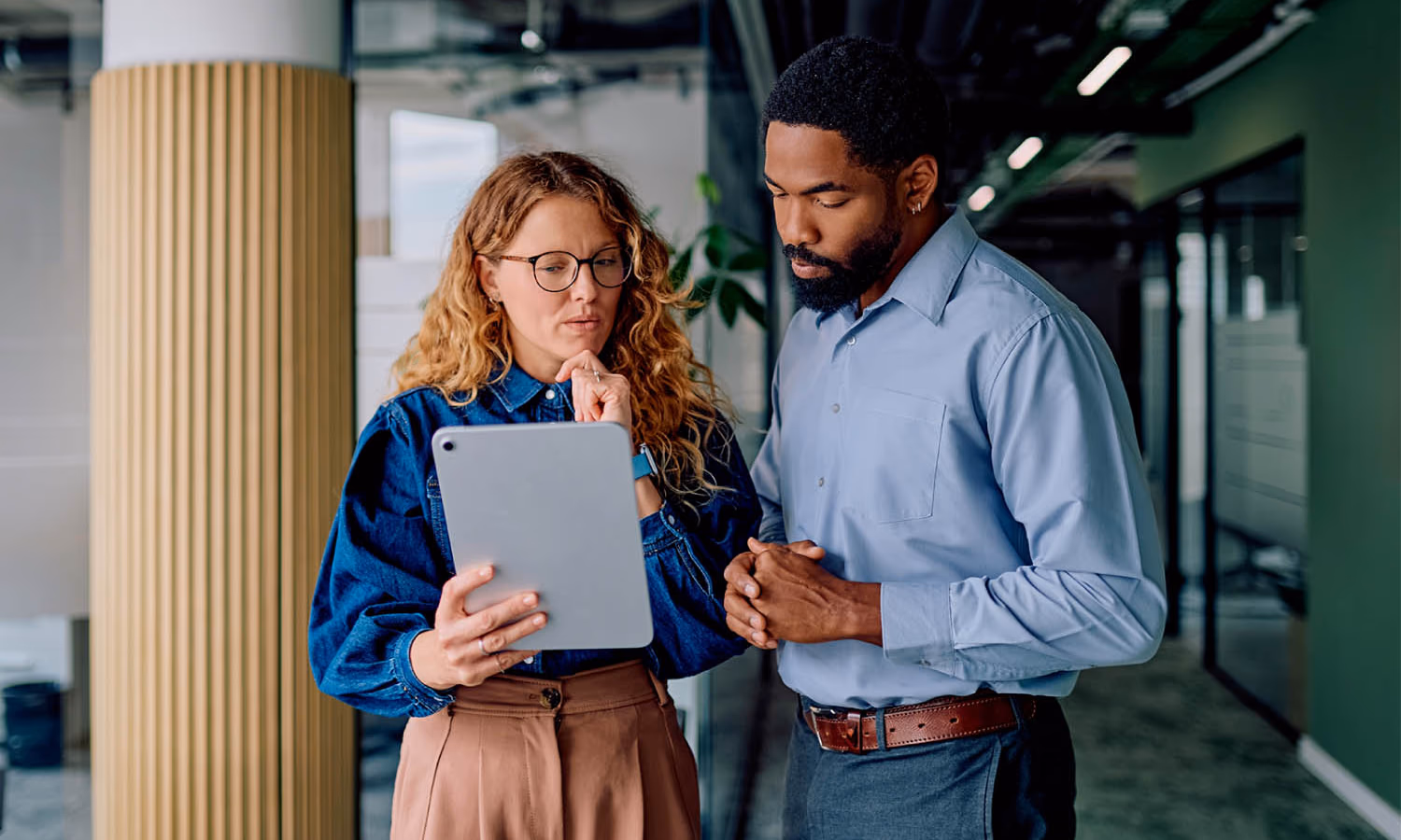 Two people in conversation as one shows the other information on a tablet.