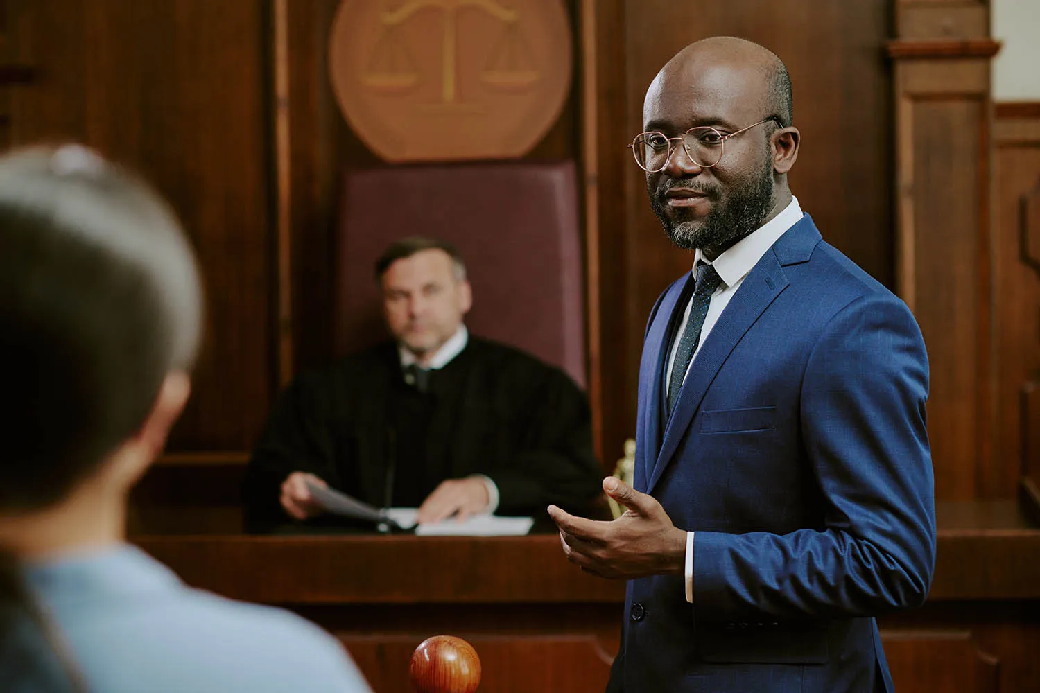 A lawyer mid-argument in a wood-paneled courtroom.