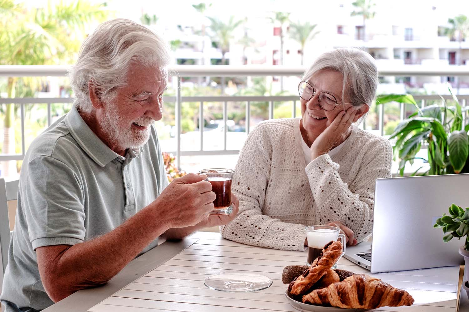 A man and a woman enjoying coffee together, doing research on renters insurance on their laptop.