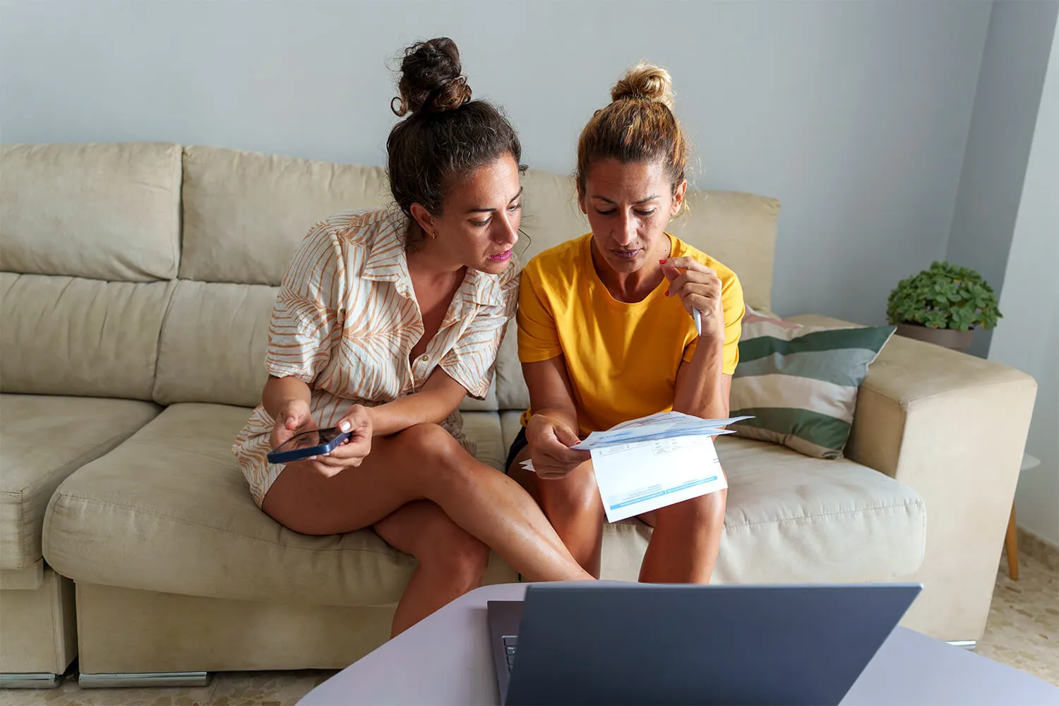Two women sitting on a couch reviewing documents
