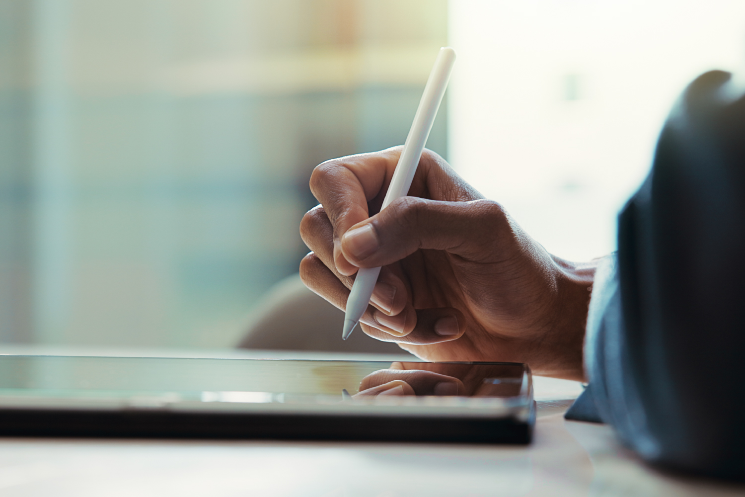 Closeup of a person writing on a tablet with an electronic pen
