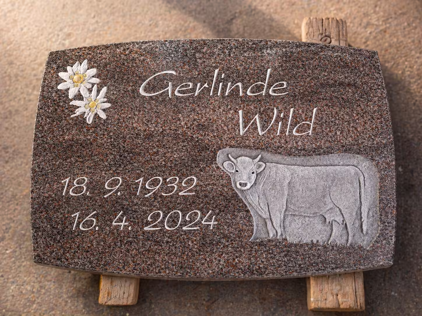 Grabstein mit einer Kuh und einer Blume als Ornamente in der Werkstatt von Hermann Naturstein, vor dem Setzen auf einem Friedhof.