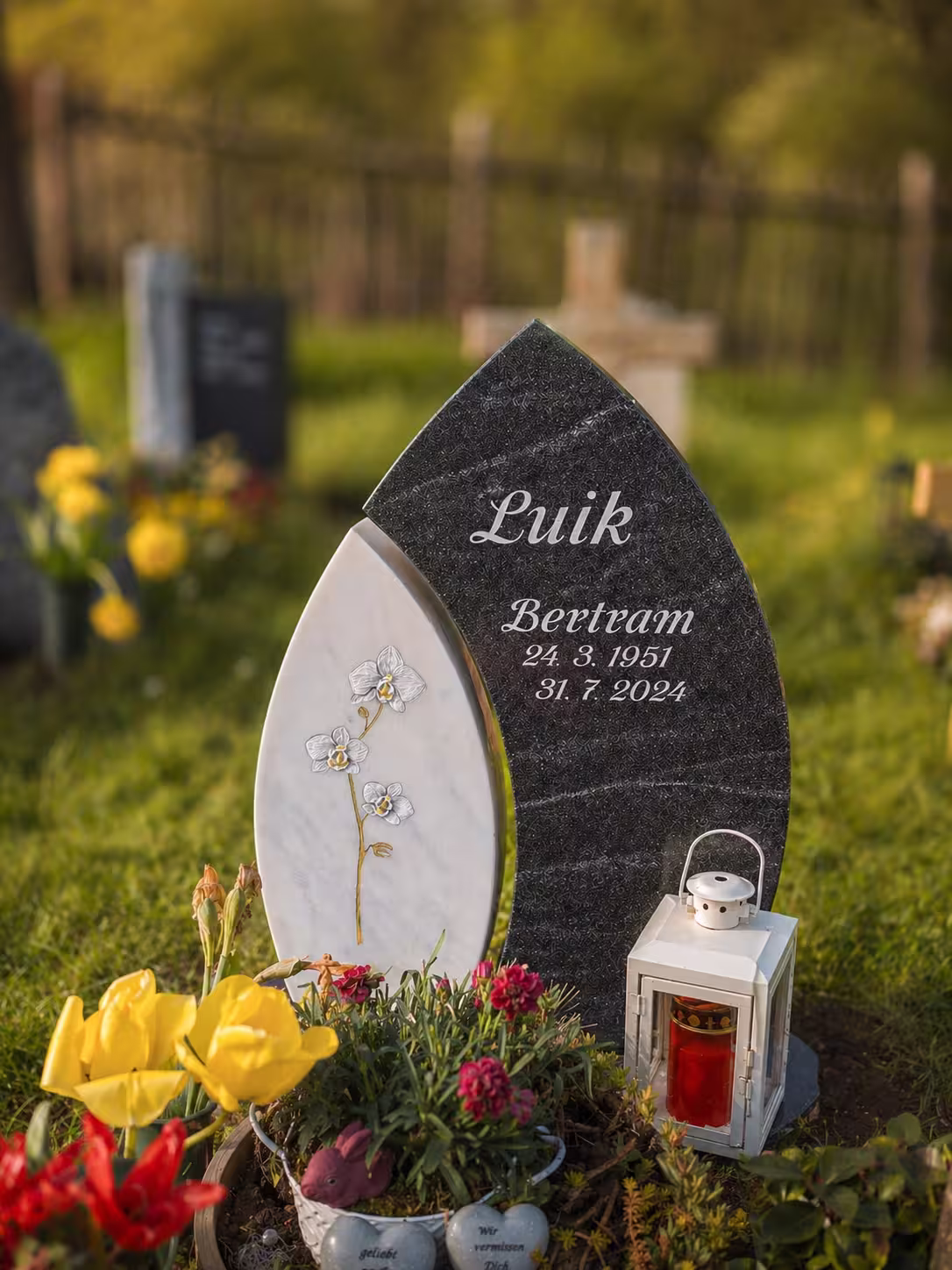Grabstein aus zwei unterschiedlichen Materialien. Mit einer Blume als Ornament.
