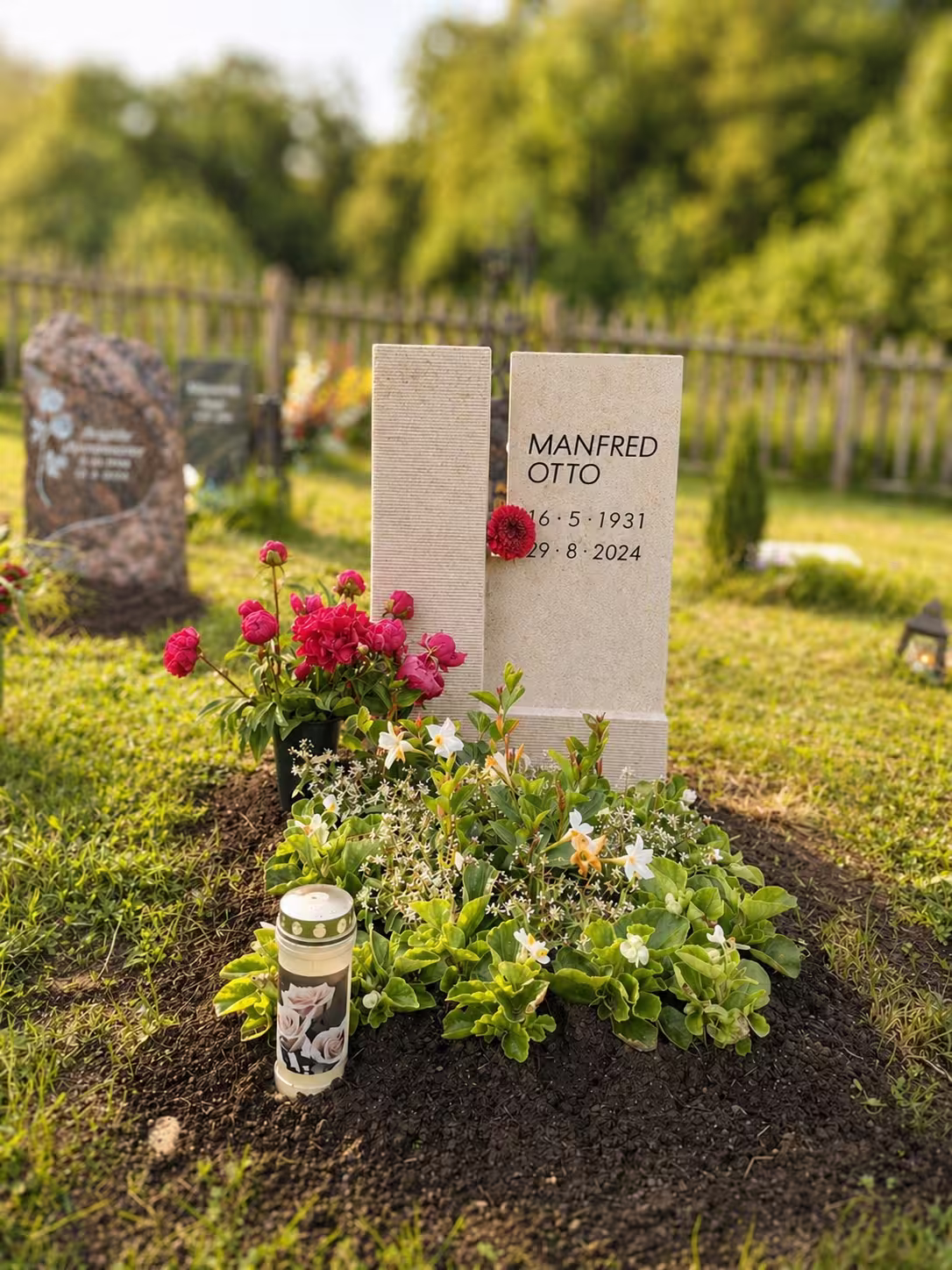 Grabstein von Hermann Naturstein auf einem Friedhof mit einem gedeckten Grab