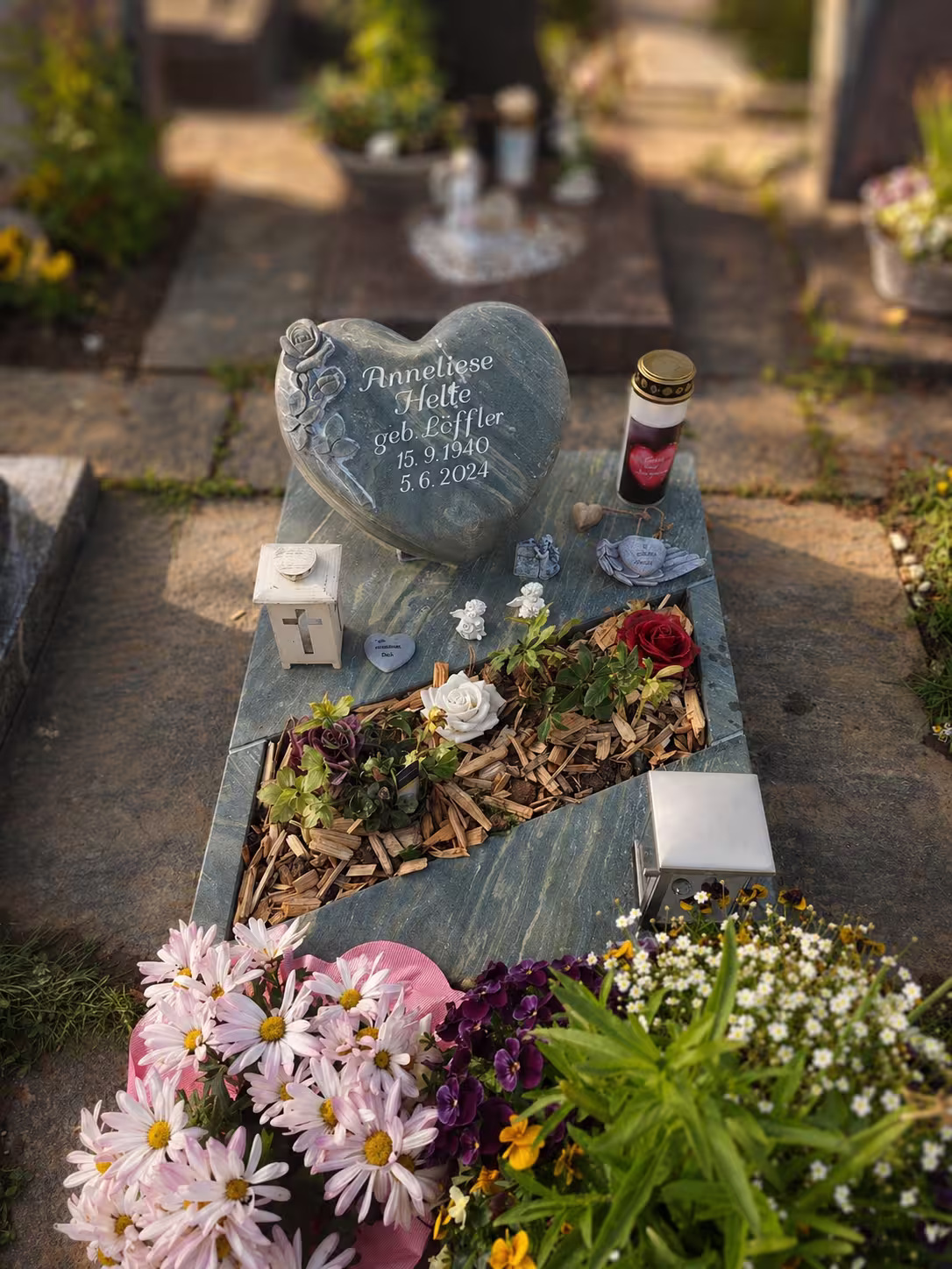 Schön dekoriertes Urnengrab, mit Herzgrabstein auf dem Friedhof in Metzingen
