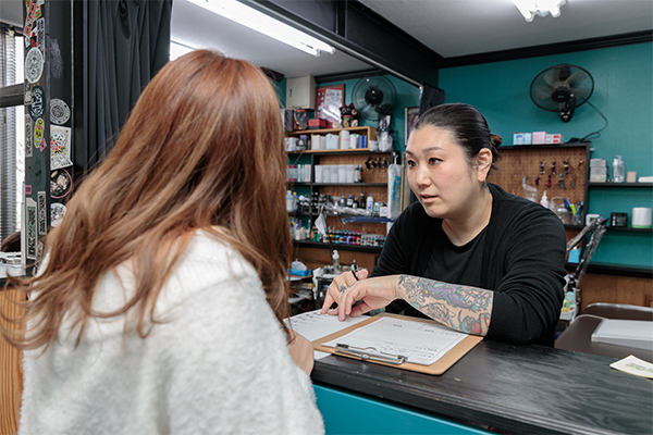 Photograph of artist Fumi having a consultation with a customer.