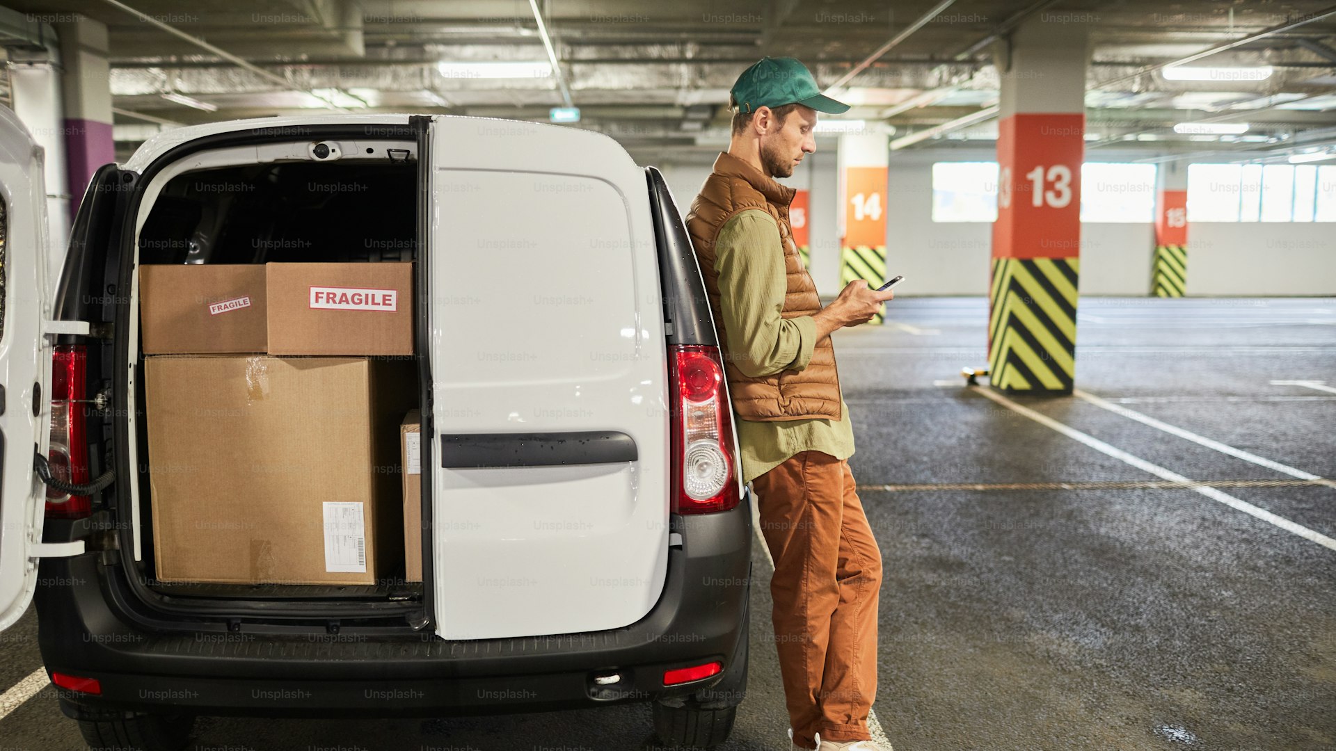 Delivery worker standing by van filled with packages in parking lot
