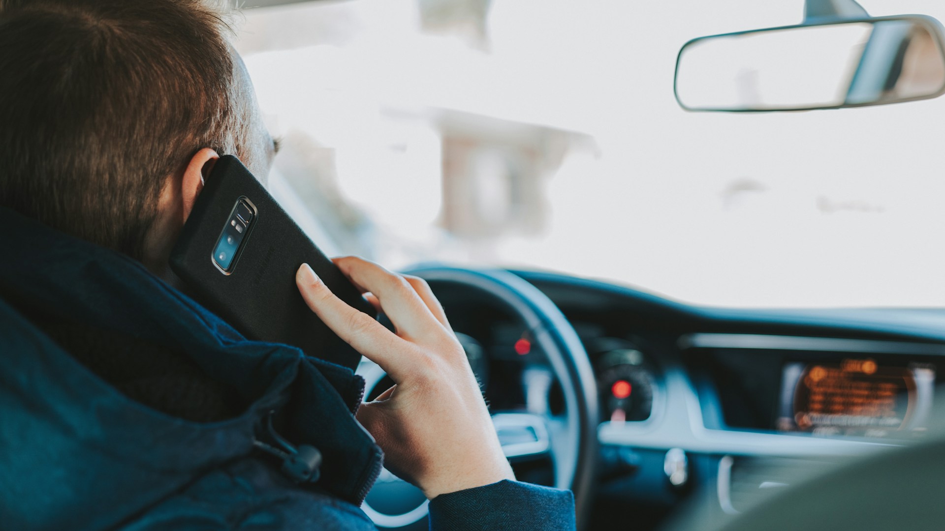 Driver sitting in car looking at phone for Spark Driver customer service