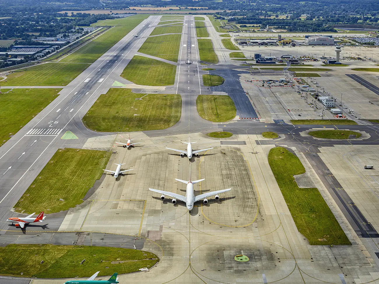 Aerial view of Gatwick Airport runway and taxiways with airplanes parked and taxiing on the tarmac.