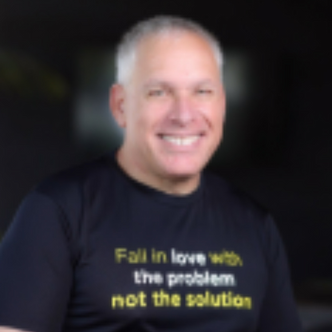 Uri Levine smiling and wearing a black t-shirt that reads "Fall in love with the problem not the solution.