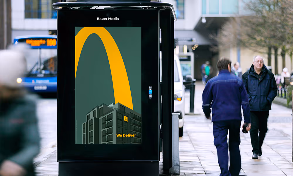 Pedestrians walk by a digital screen located at a bus shelter