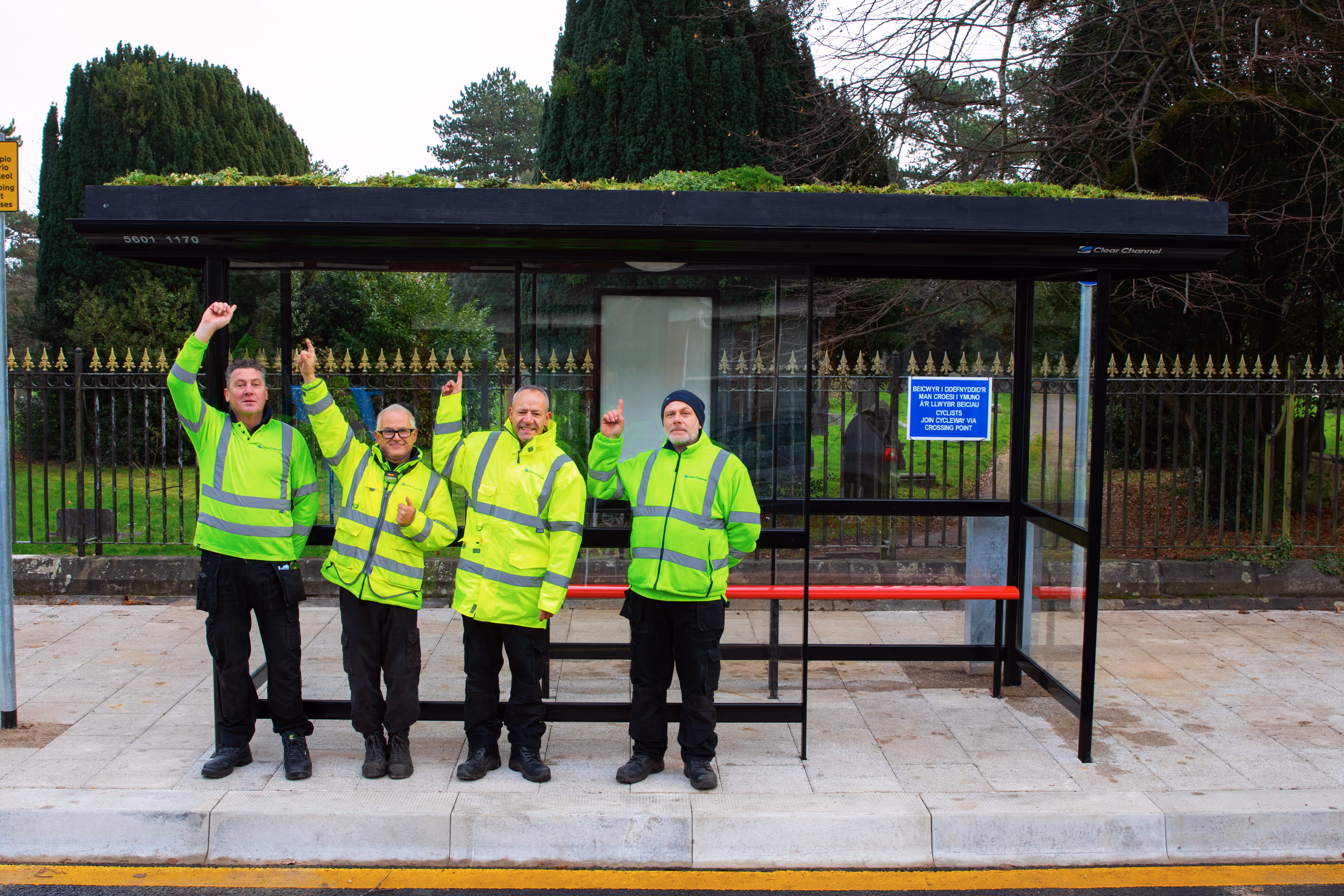 A group of operatives in reflective jackets standing in front of a Living Roof bus stop