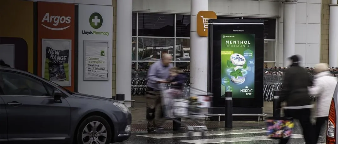 Nordic Sprint's ad outside of a Sainsbury's as people walk past