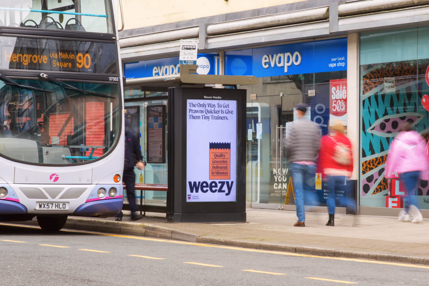 Weezy advertising on a digital bus stop with a bus stopped at the traffic lights