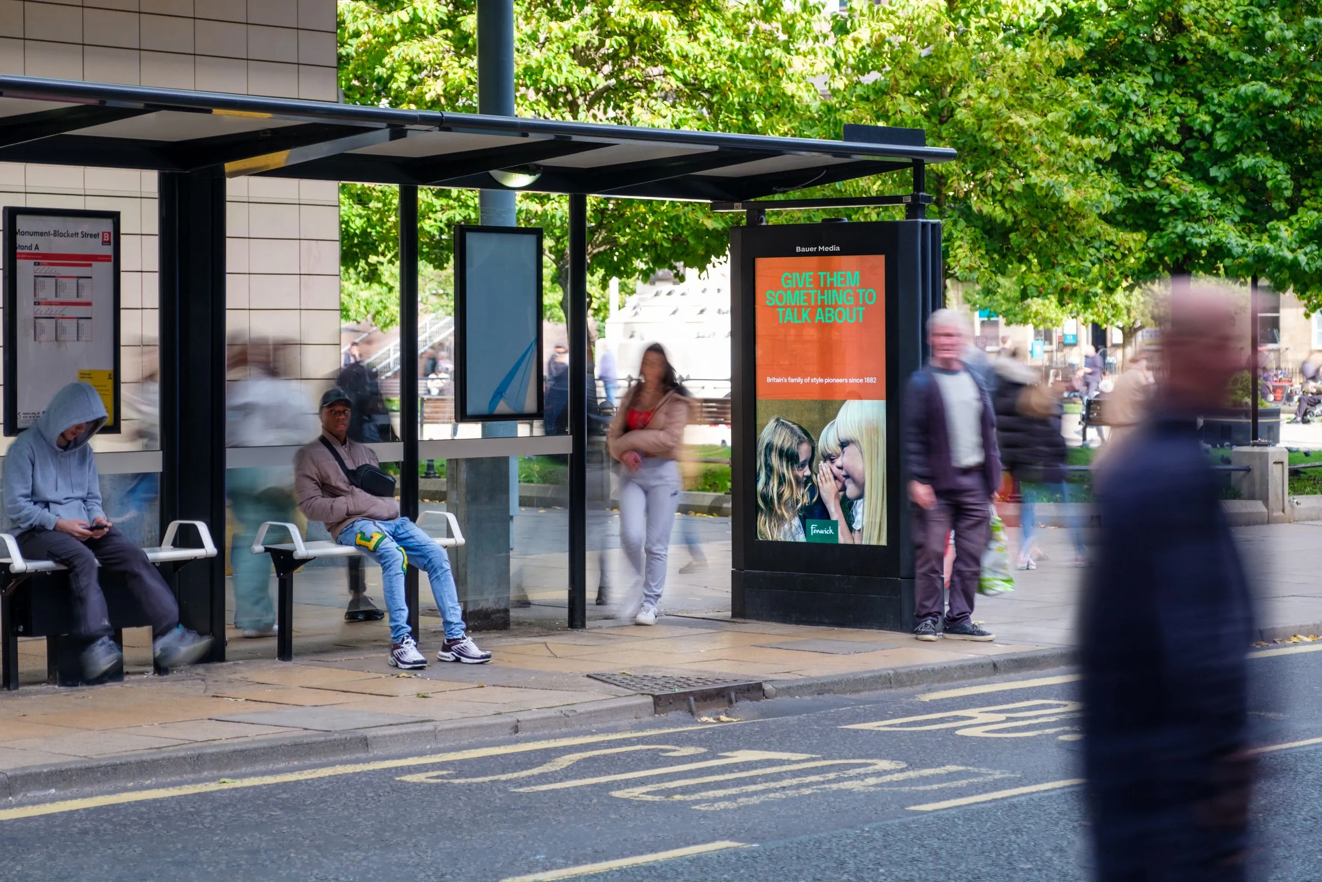 Digital bus shelter with people sat within the shelter