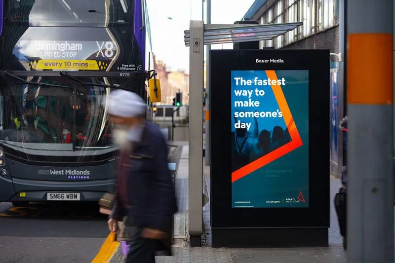 Avanti West Coast's blue orange and grey travel advertisement with a bus stationed at a bus stop