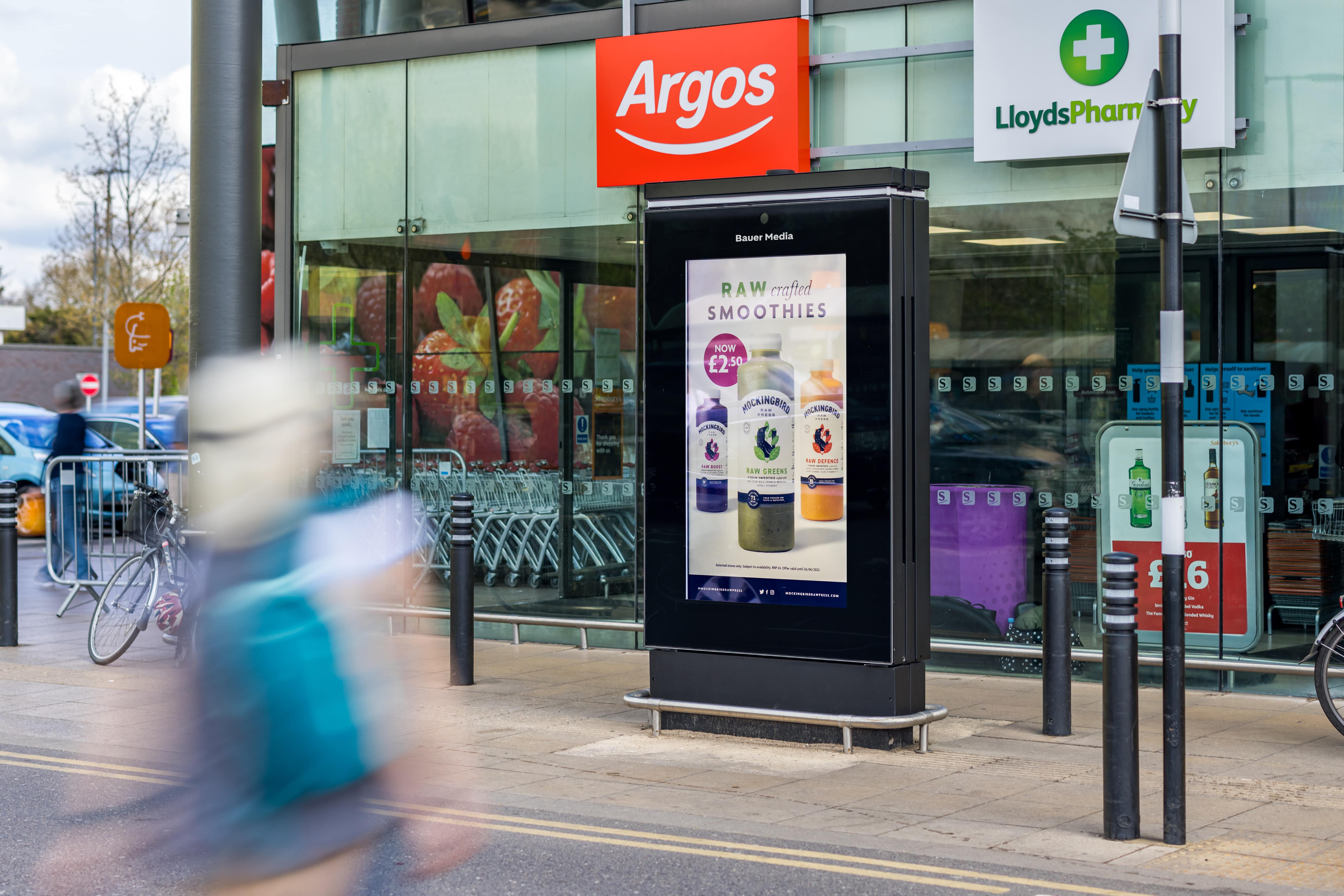 Digital advertisement outside of an Asda with shoppers walking by