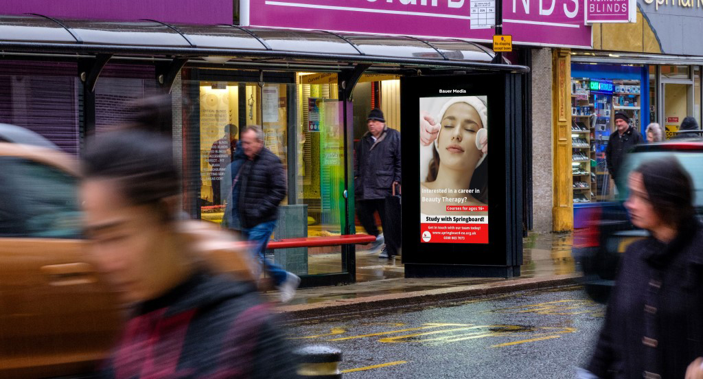 Springboard advertising on a busy digital bus shelter screen in the rain