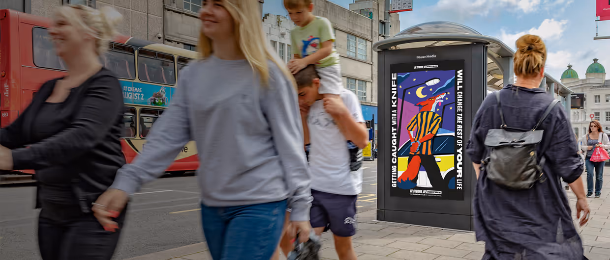 An Adshel Live digital screen with people walking past