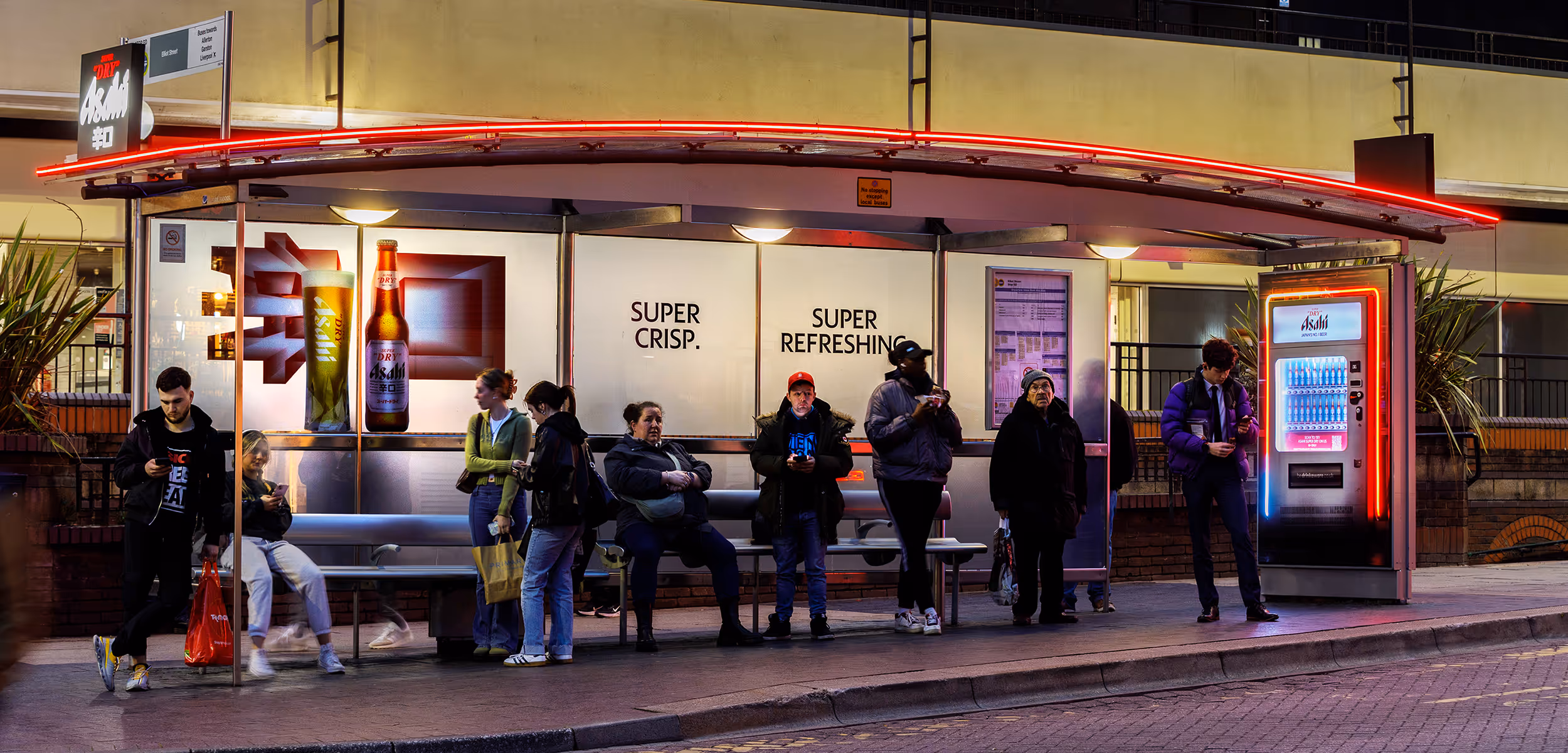 People at a bus shelter, which is creatively wrapped by advertiser Asahi