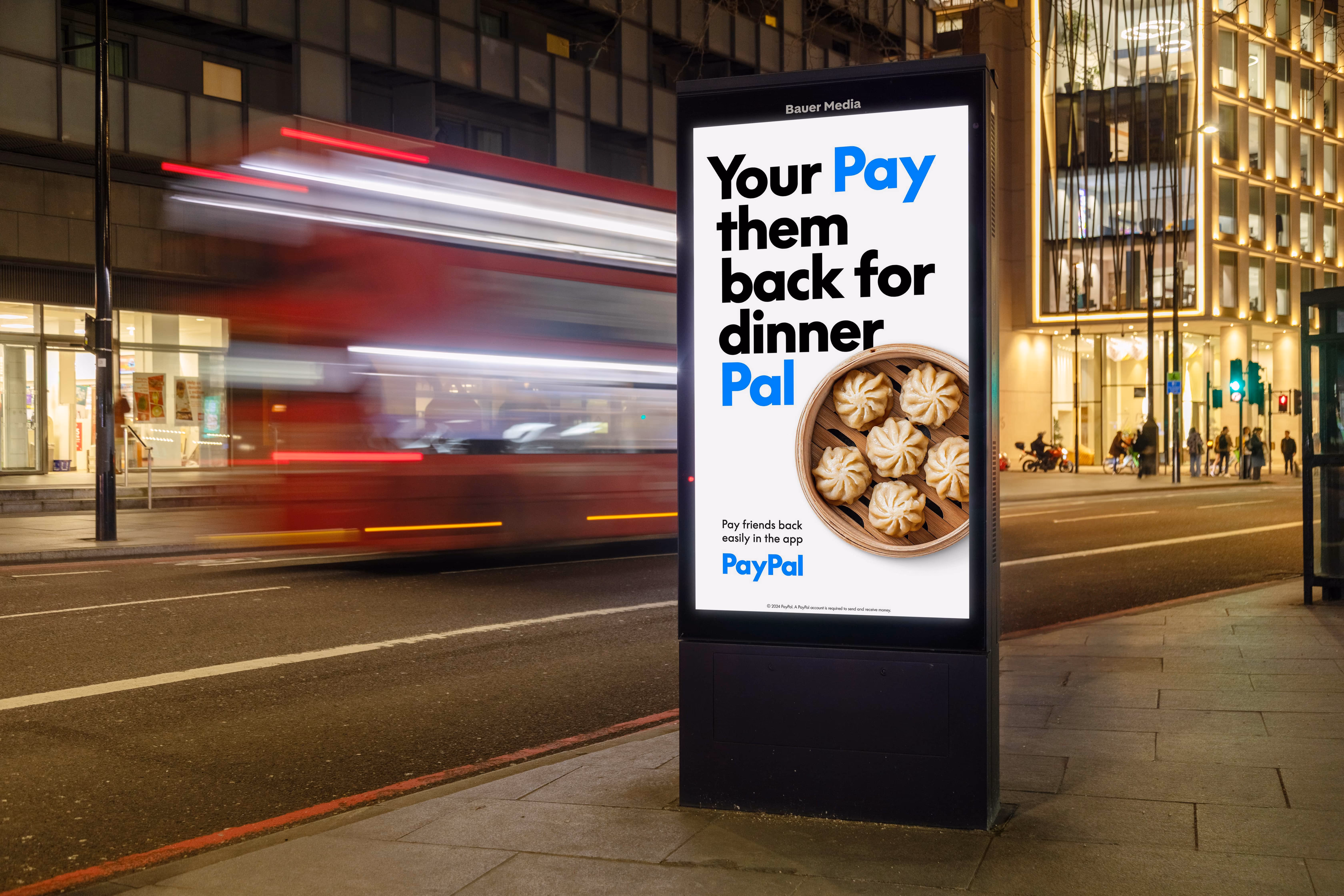 Bus stop digital advertisement for PayPal encouraging to pay friends back for dinner, with image of a basket of dumplings.