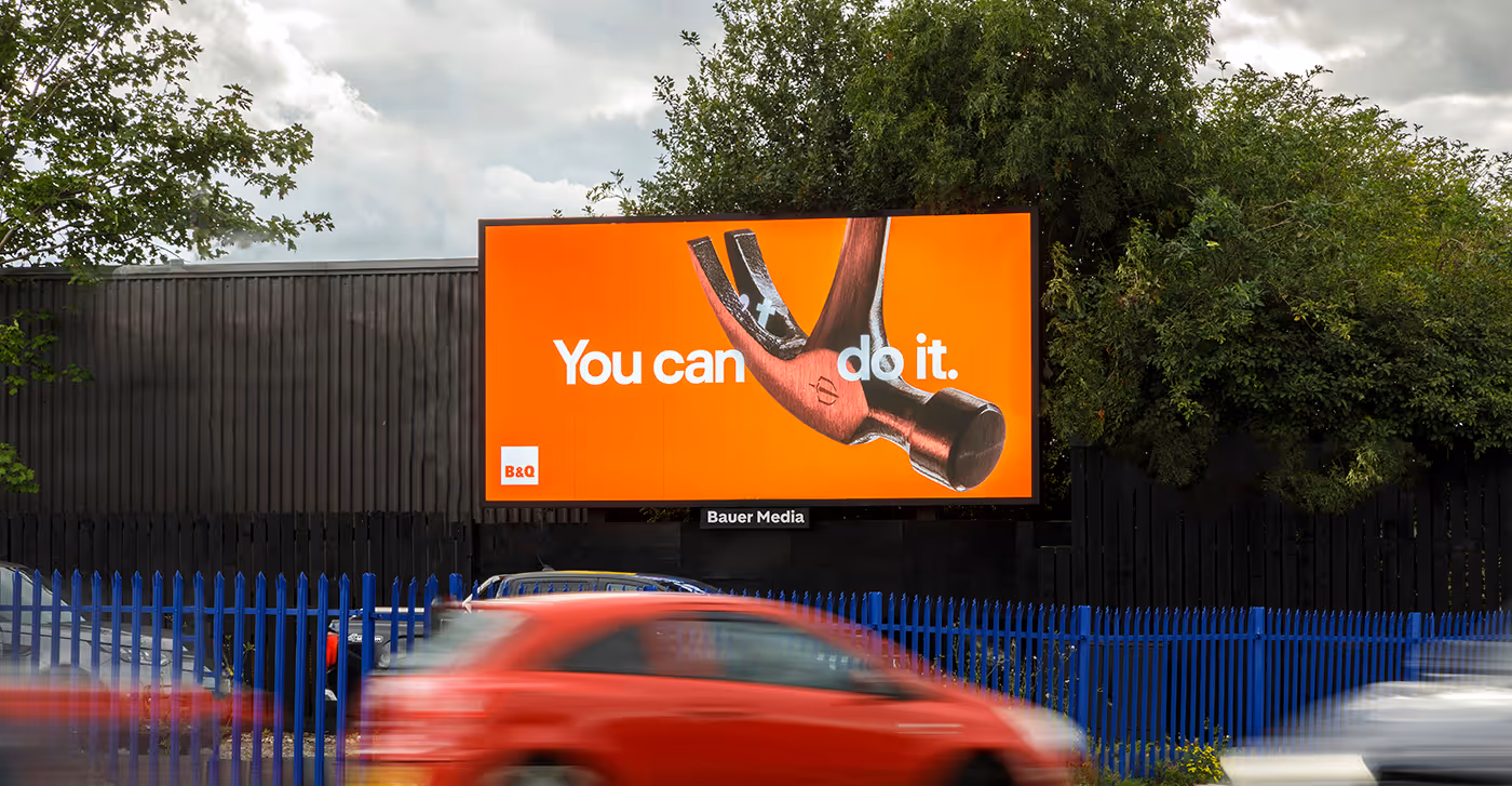 You can do it B&Q advert with a hammer on a digital billboard. A red car drives past.