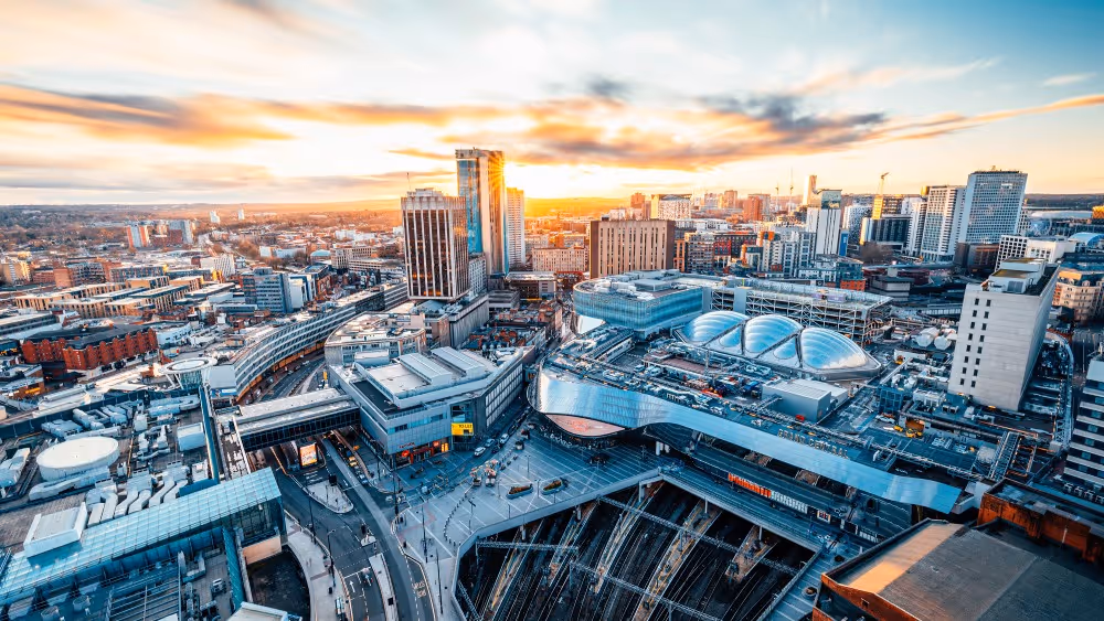 Aerial view of a modern cityscape with tall buildings, urban infrastructure, and a vibrant sunset sky.