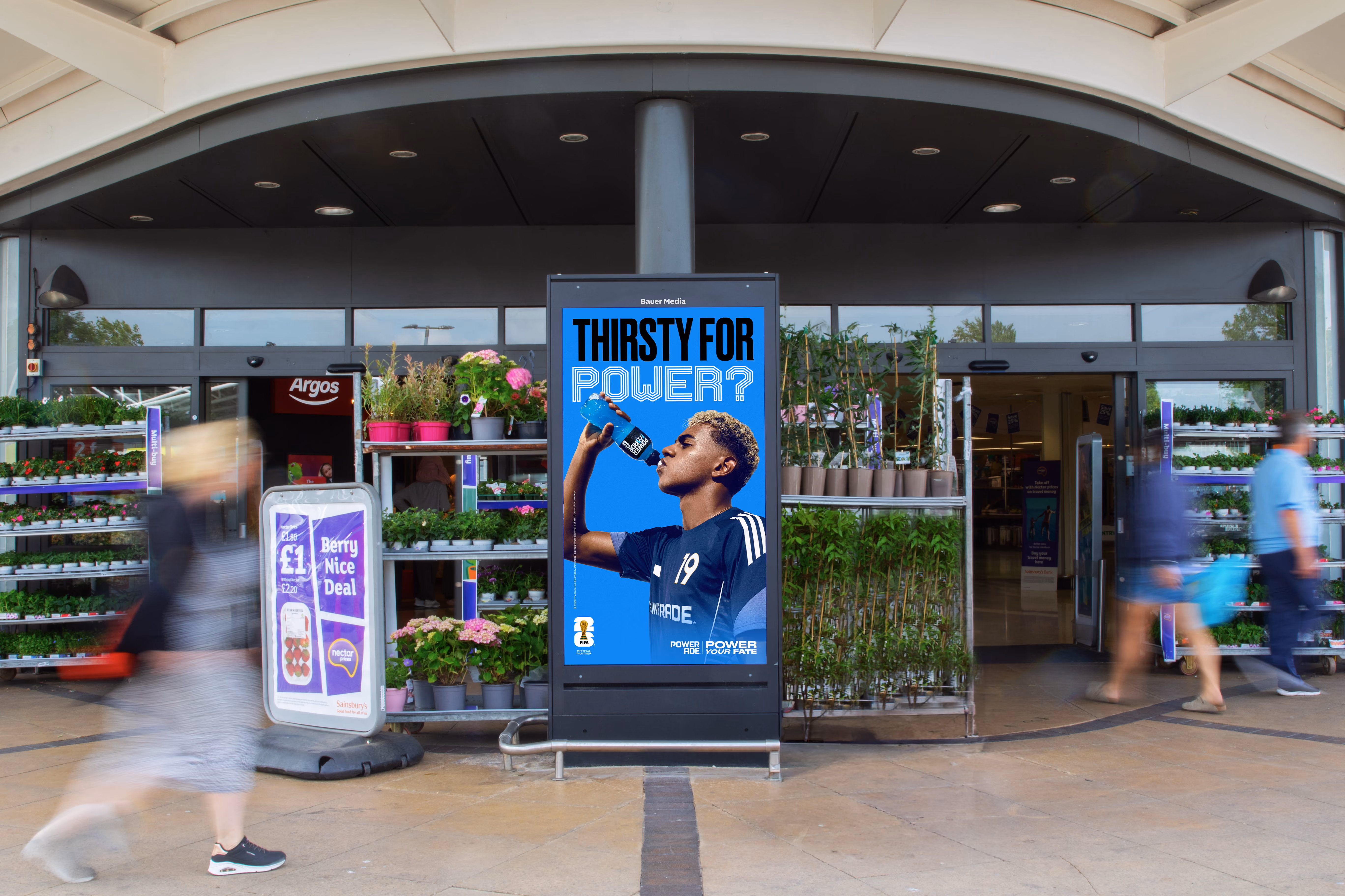 Supermarket entrance with a digital ad showing a man drinking Powerade under the text 'Thirsty for power?'
